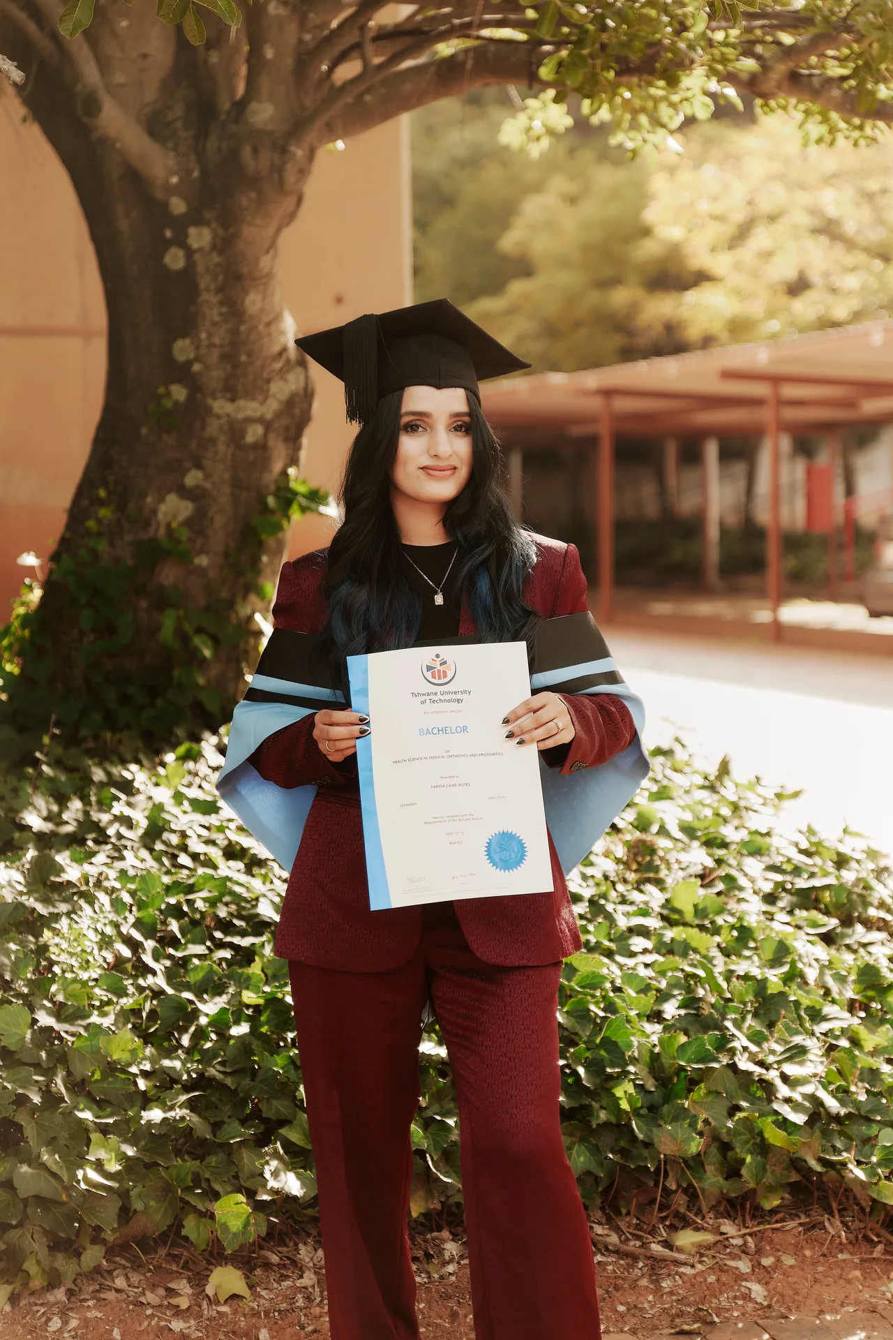 Farida Cajee-Botes on her graduation day, wearing her academic cap and gown and holding her qualification certificate